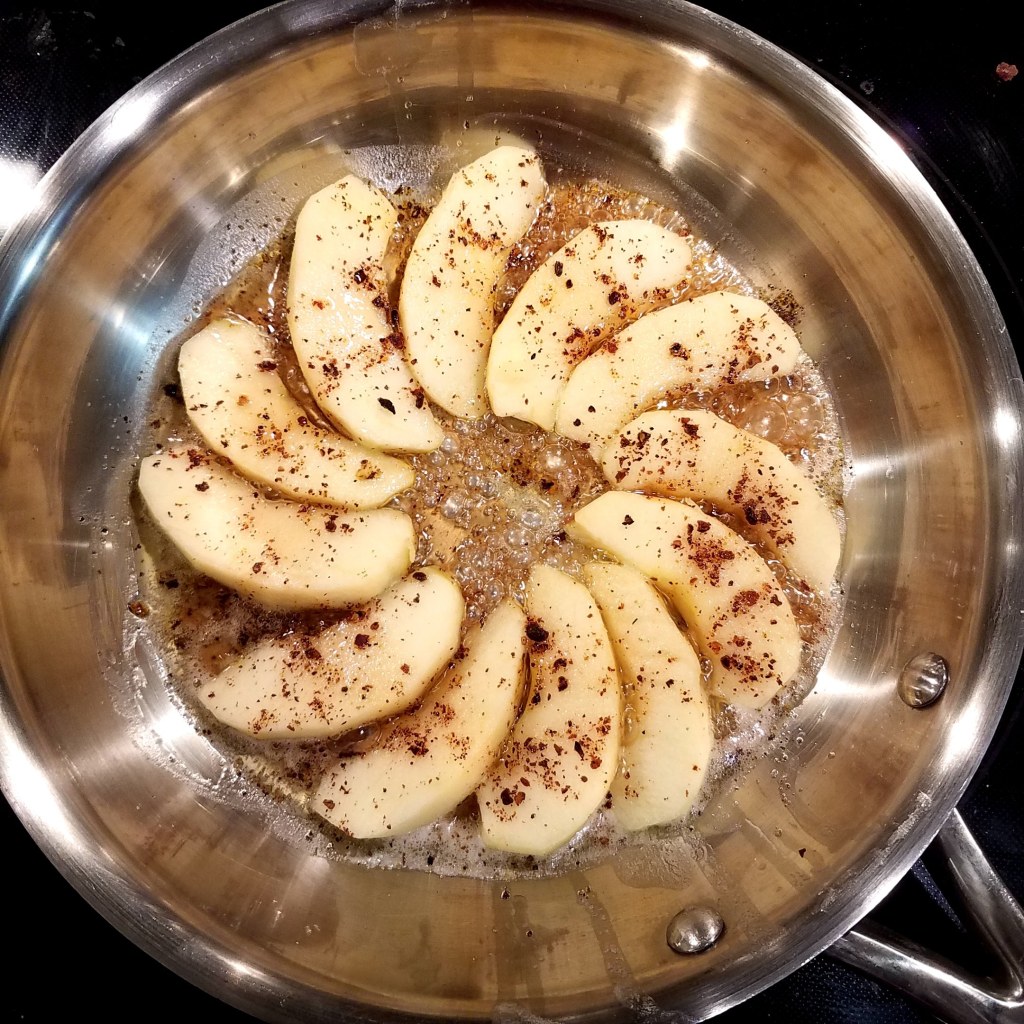 Spicebush and apple slices cooking in the pan